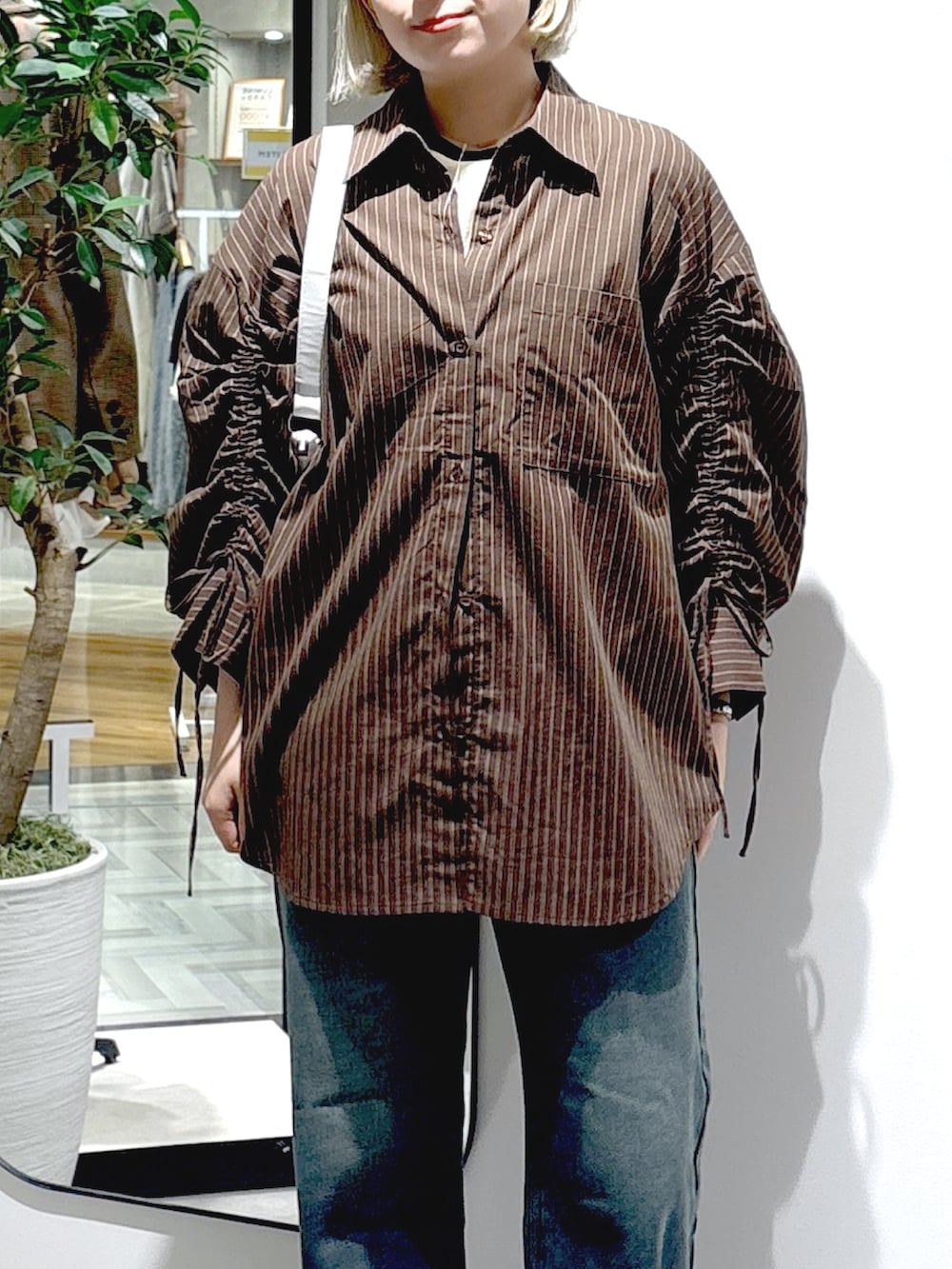 ブラウン系のシャツ/ブラウス、ブルー系のデニムパンツ、ホワイト系のTシャツ/カットソーを着用したレディースの秋コーディネートの5枚目の写真