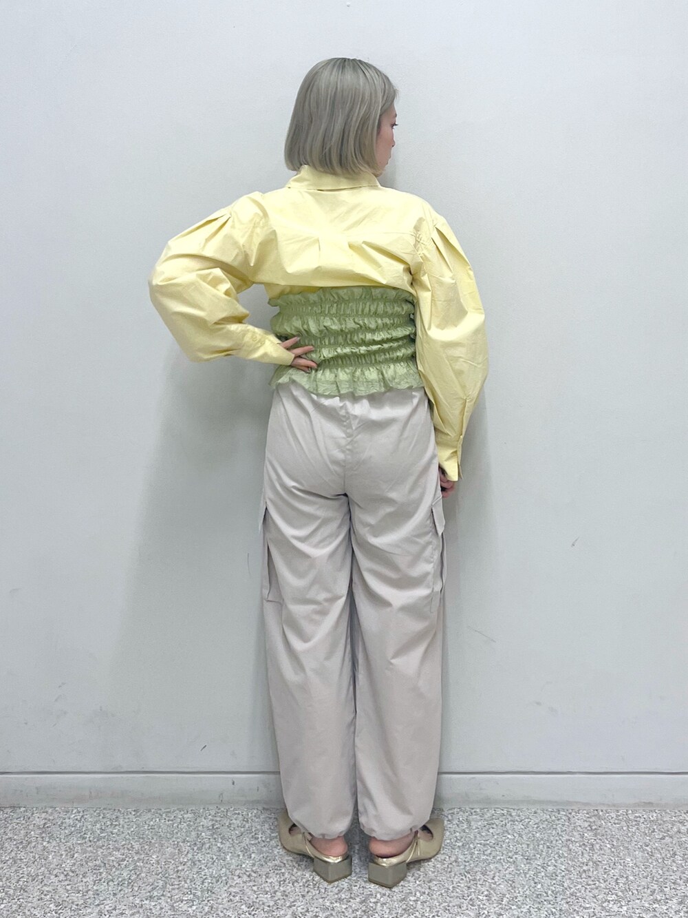 ベージュ系のカーゴパンツ、ゴールド系のパンプス、グリーン系のキャミソールを着用したレディースの春コーディネートの2枚目の写真