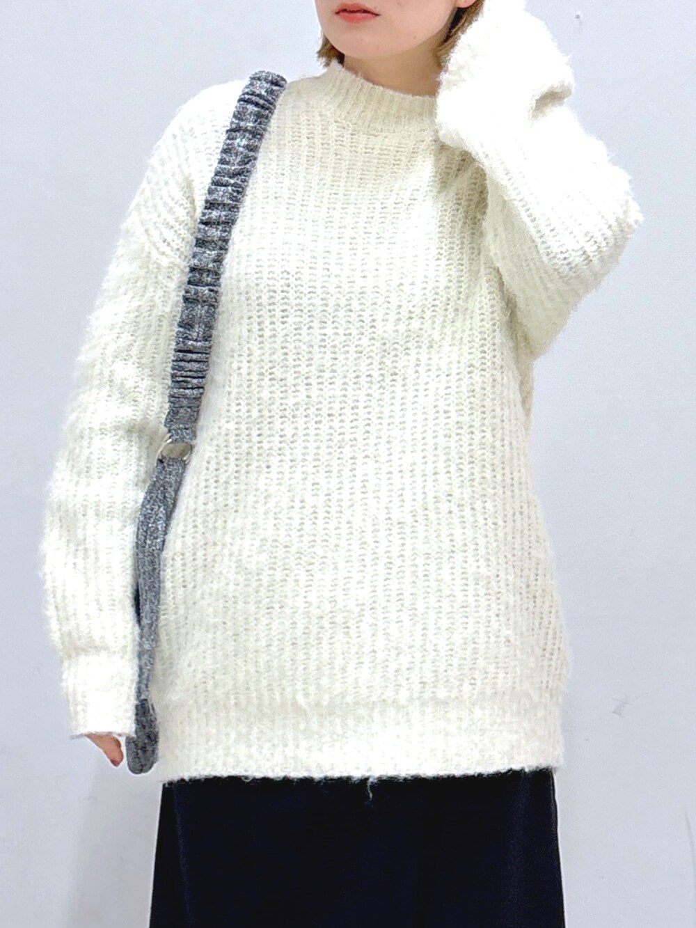 ブラック系のスカート、ホワイト系のニット/セーター、シルバー系のショルダーバッグを着用したレディースの冬コーディネートの4枚目の写真