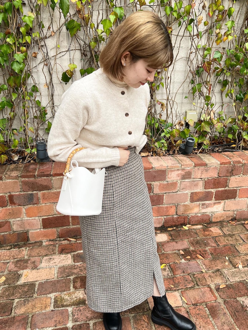 ベージュ系のスカート、ホワイト系のニット/セーター、ホワイト系のショルダーバッグを着用したレディースの冬コーディネートの3枚目の写真