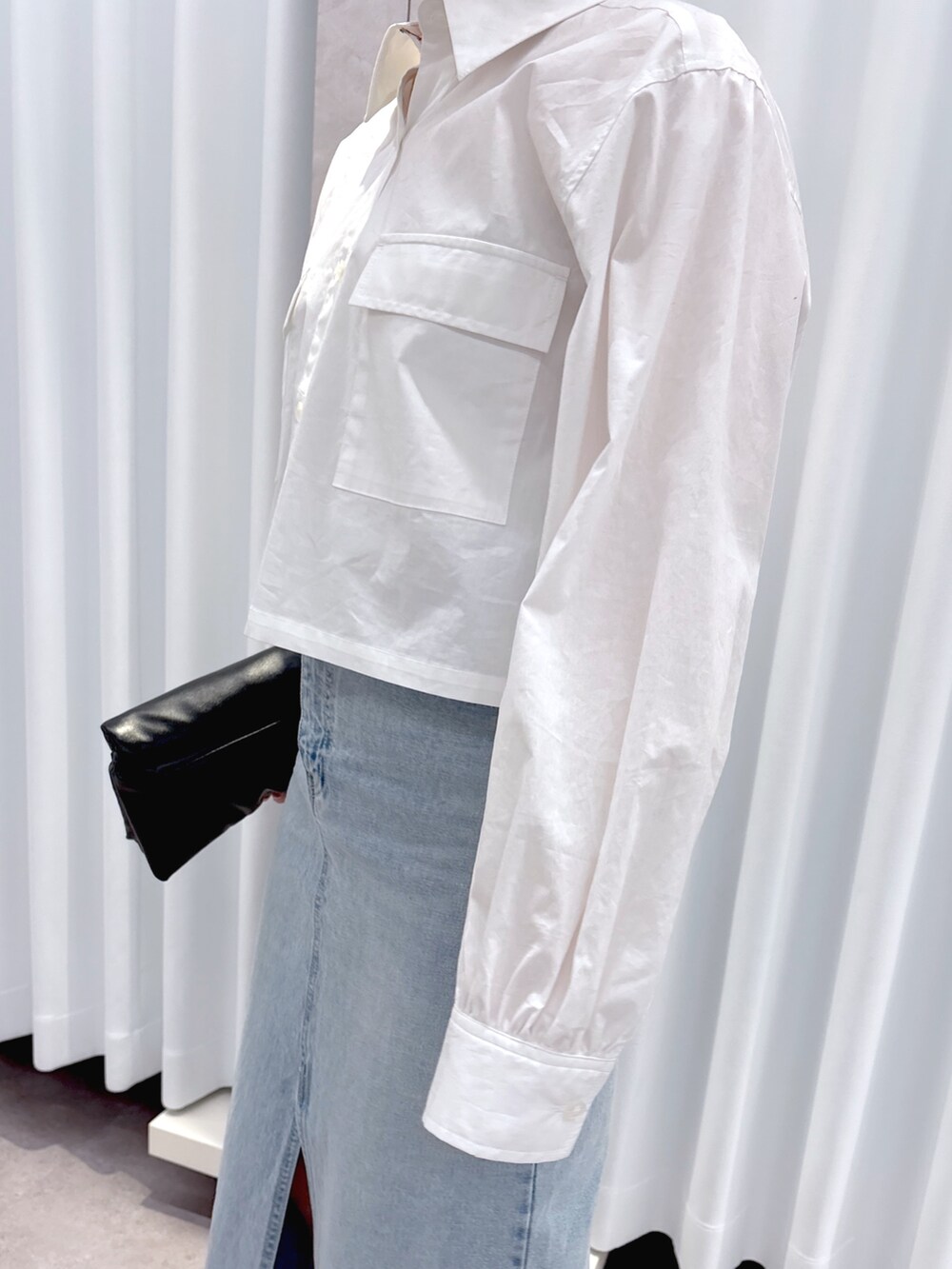 ブラック系のショルダーバッグ、ブルー系のデニムスカート、ホワイト系のシャツ/ブラウスを着用したレディースの春コーディネートの7枚目の写真