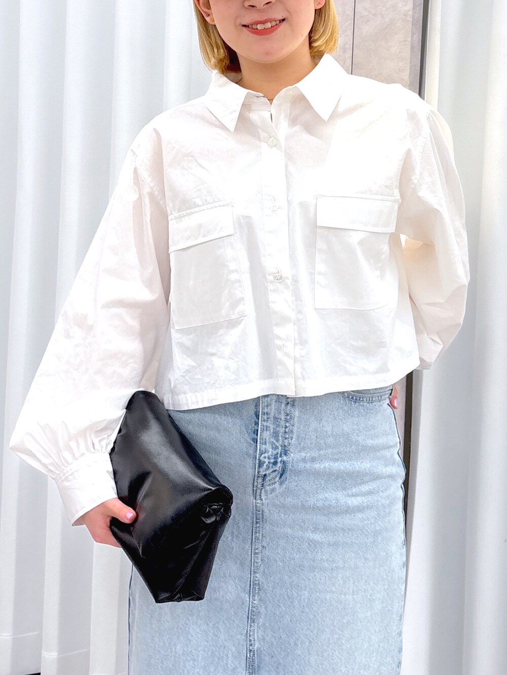 ブラック系のショルダーバッグ、ブルー系のデニムスカート、ホワイト系のシャツ/ブラウスを着用したレディースの春コーディネートの6枚目の写真