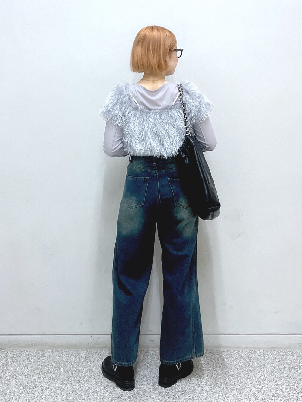 ブルー系のデニムパンツ、ベージュ系のブーツ、ブラック系のトートバッグを着用したレディースの秋コーディネートの3枚目の写真