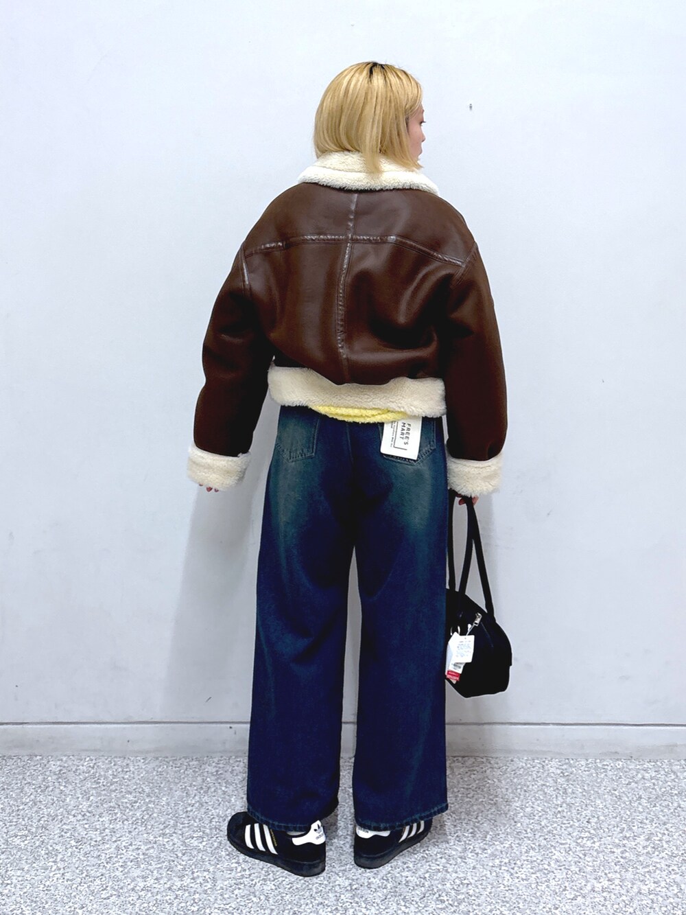 ブルー系のデニムパンツ、ブラウン系のその他アウター、ブラック系のトートバッグを着用したレディースの冬コーディネートの3枚目の写真