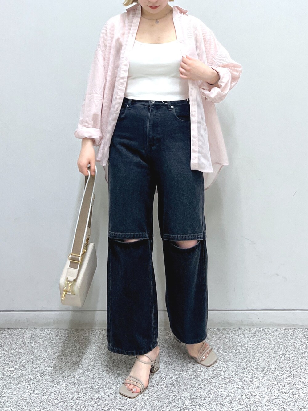 ブラック系のデニムパンツ、グレー系のサンダル、ホワイト系のハンドバッグを着用したレディースの夏コーディネートの3枚目の写真