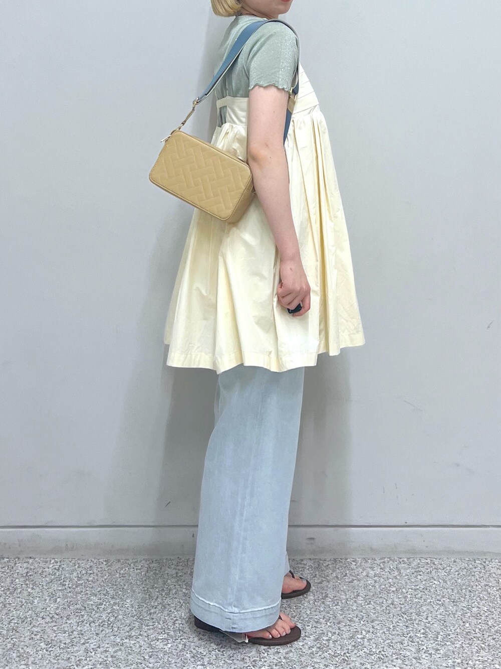 ブルー系のデニムパンツ、ホワイト系のハンドバッグ、グリーン系のTシャツ/カットソーを着用したレディースの夏コーディネートの3枚目の写真