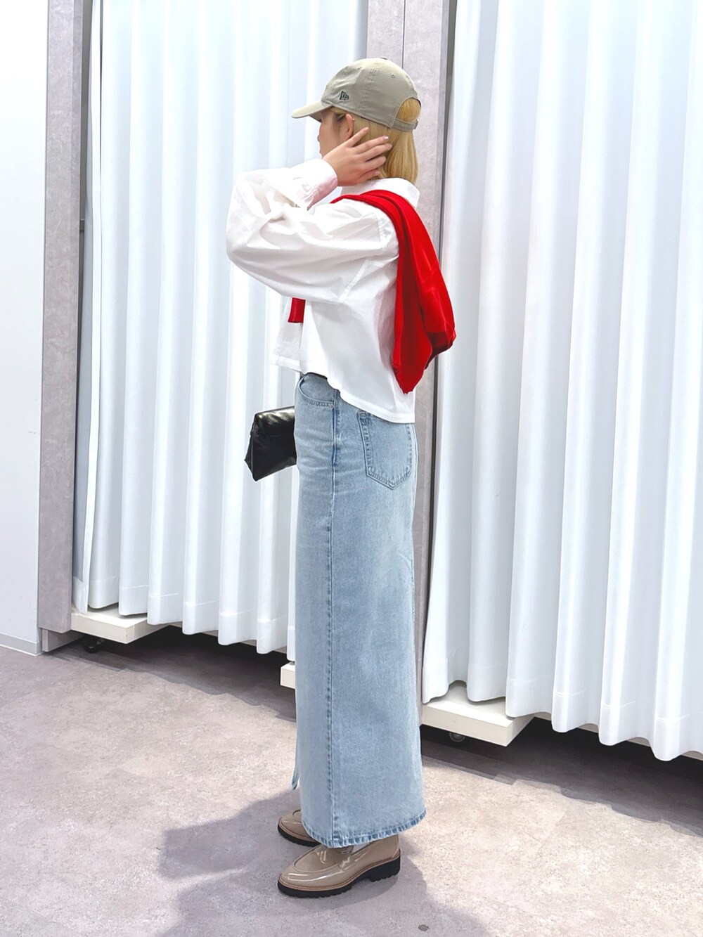 ブラック系のショルダーバッグ、ブルー系のデニムスカート、ホワイト系のシャツ/ブラウスを着用したレディースの春コーディネートの3枚目の写真