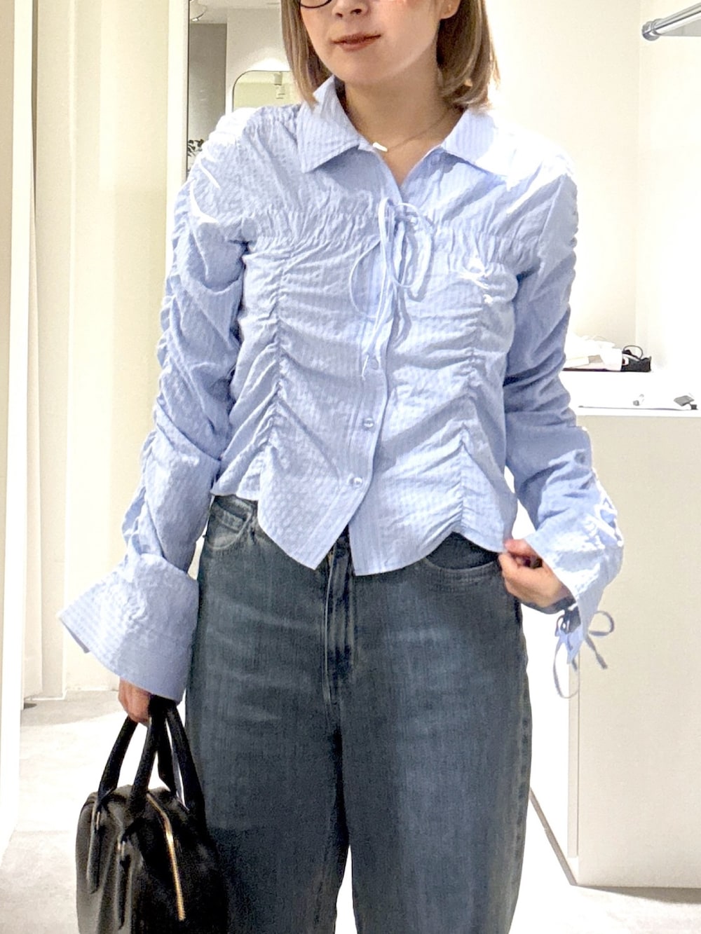 ブルー系のシャツ/ブラウス、ブルー系のデニムパンツ、ブラック系のハンドバッグを着用したレディースの春コーディネートの4枚目の写真