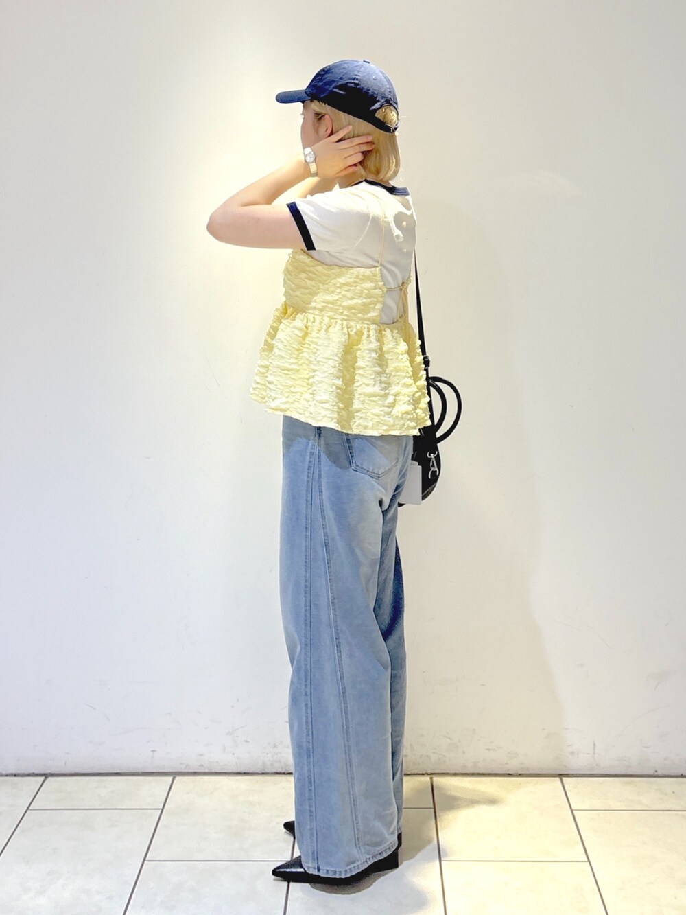 ブラック系のパンプス、ブルー系のデニムパンツ、ブラック系のトートバッグを着用したレディースの夏コーディネートの2枚目の写真