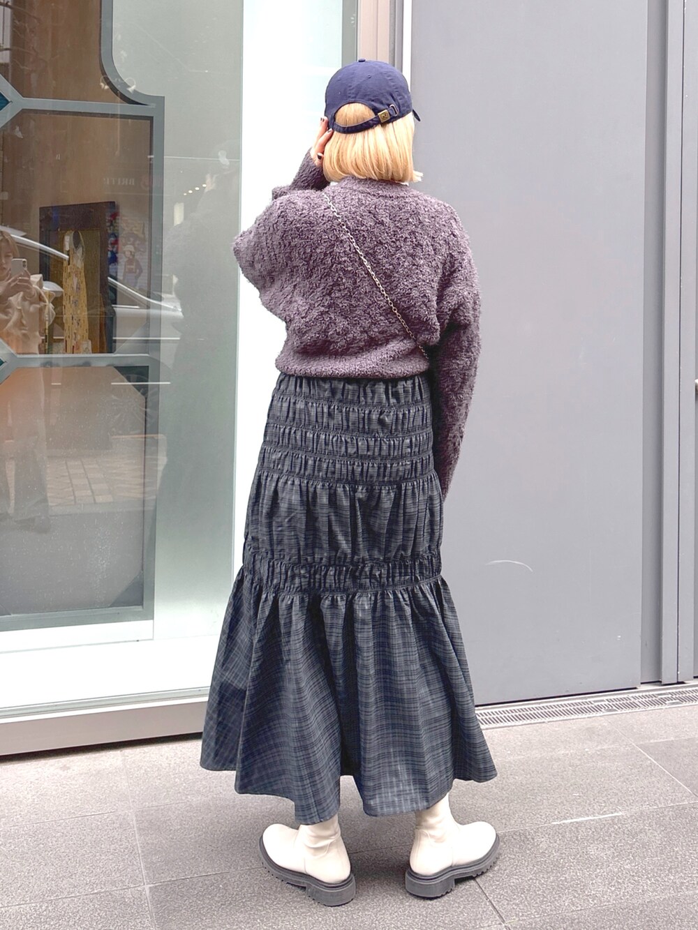 グレー系のスカート、グレー系のニット/セーター、ブラック系のショルダーバッグを着用したレディースの冬コーディネートの2枚目の写真