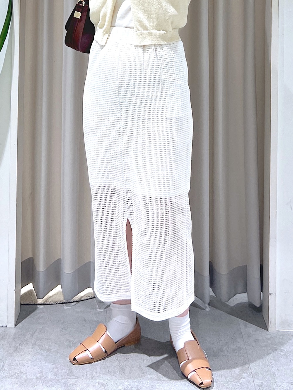 ベージュ系のスリッポン、ベージュ系のショルダーバッグ、ホワイト系のスカートを着用したレディースの夏コーディネートの4枚目の写真