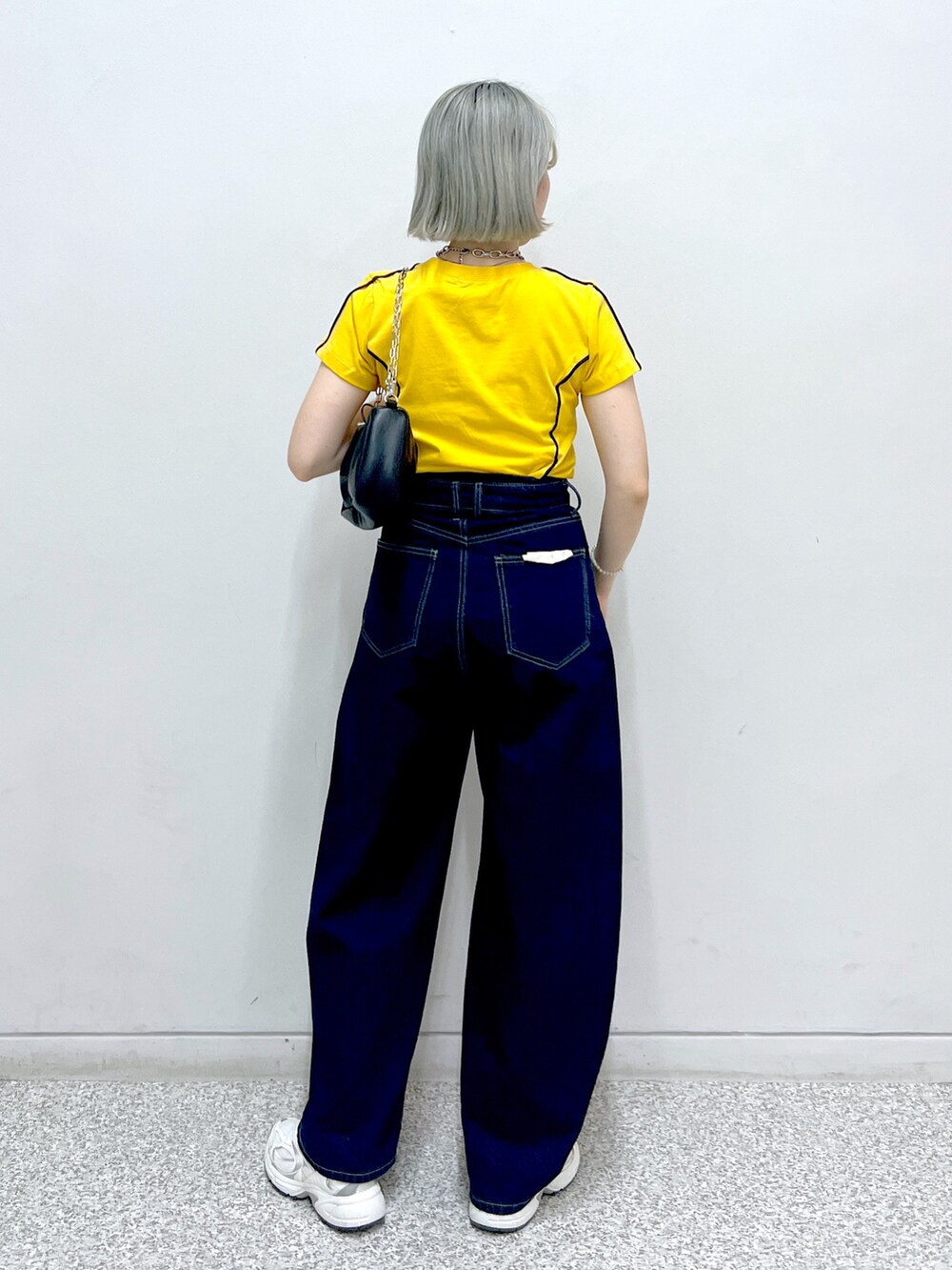 ブルー系のデニムパンツ、シルバー系のハンドバッグ、オレンジ系のTシャツ/カットソーを着用したレディースの秋コーディネートの3枚目の写真