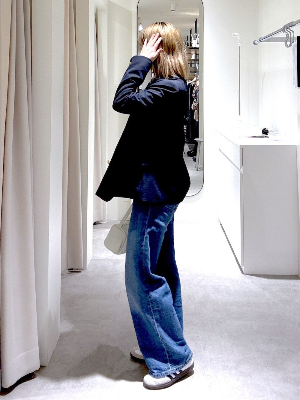 ホワイト系のハンドバッグ、ブルー系のテーラードジャケット、グレー系のニット/セーターを着用したレディースの春コーディネートの2枚目の写真