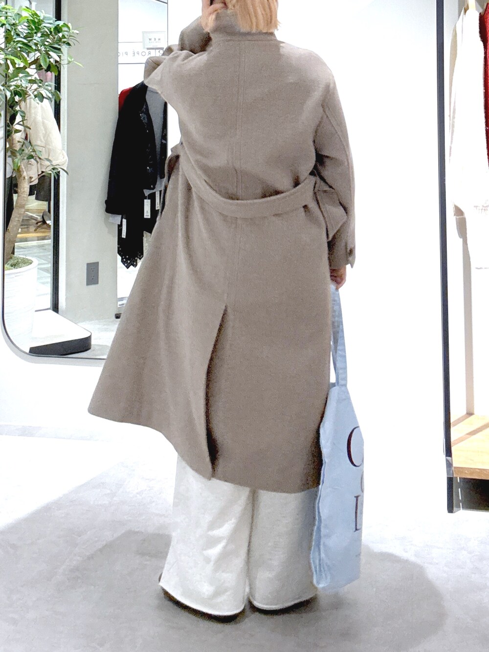 ブラウン系のステンカラーコート、ホワイト系のスウェットパンツ、ブルー系のトートバッグを着用したレディースの秋コーディネートの5枚目の写真