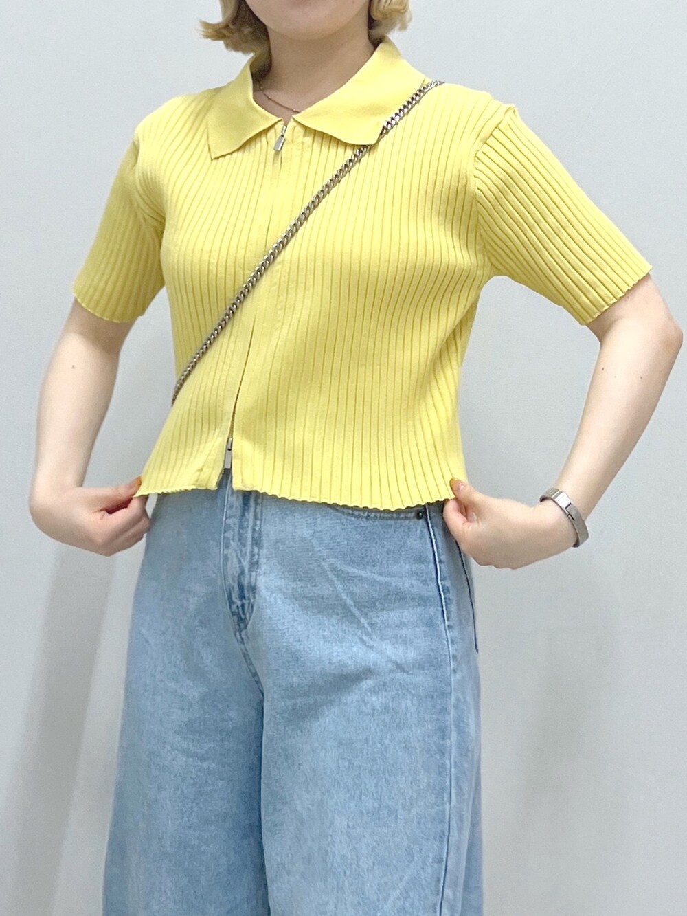 ブルー系のデニムパンツ、ブラック系のショルダーバッグ、イエロー系のニット/セーターを着用したレディースの夏コーディネートの4枚目の写真