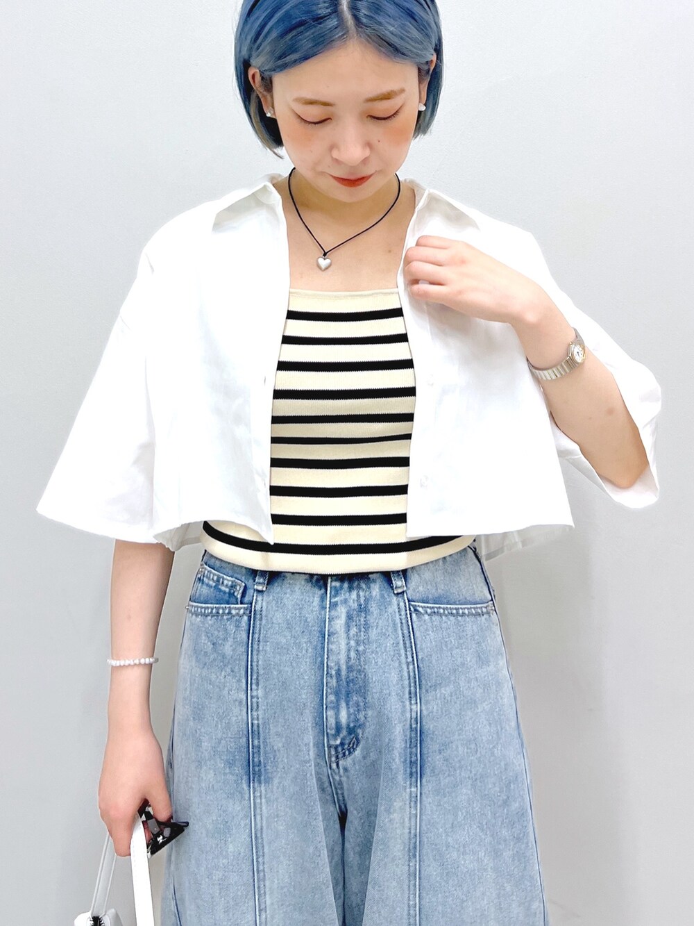 ホワイト系のハンドバッグ、ブルー系のデニムパンツ、ホワイト系のシャツ/ブラウスを着用したレディースの夏コーディネートの5枚目の写真