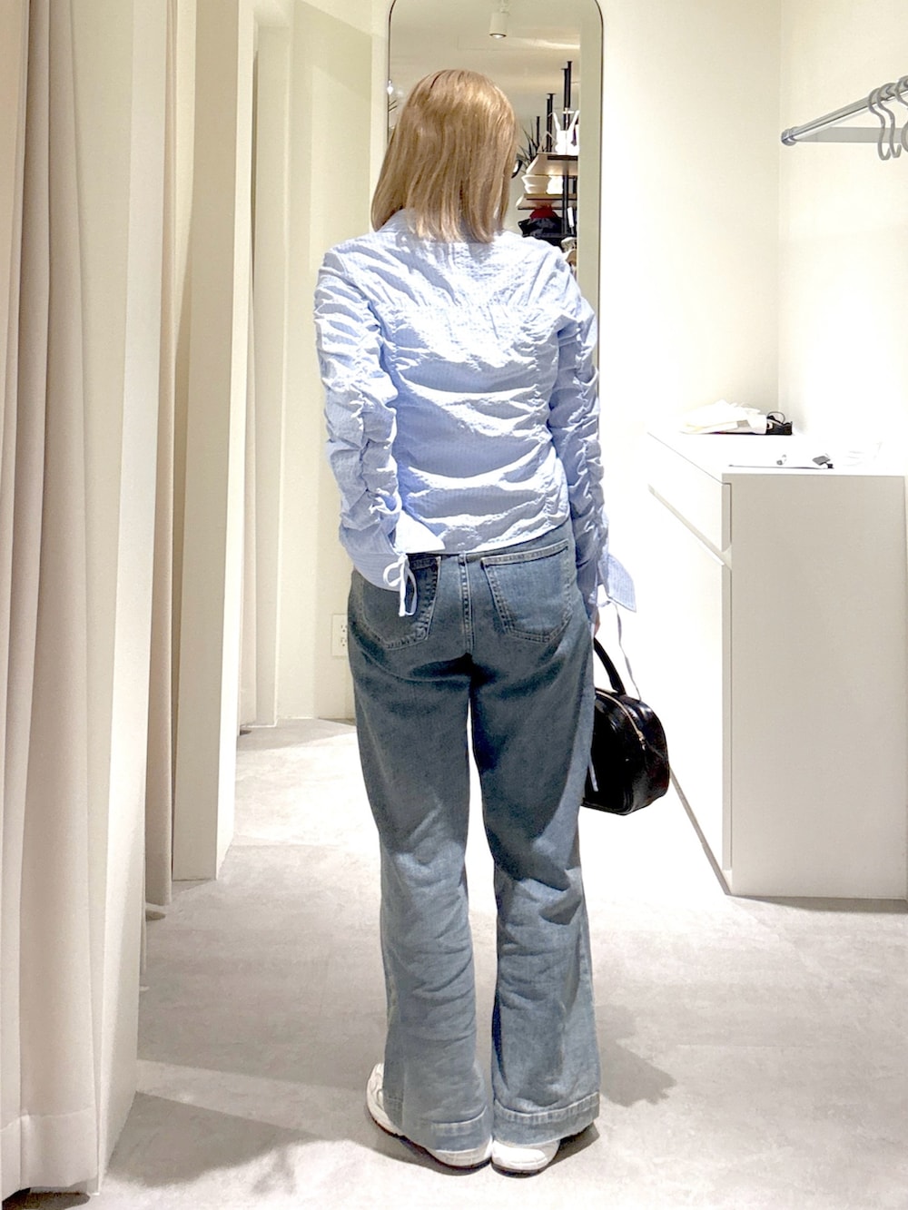 ブルー系のシャツ/ブラウス、ブルー系のデニムパンツ、ブラック系のハンドバッグを着用したレディースの春コーディネートの3枚目の写真