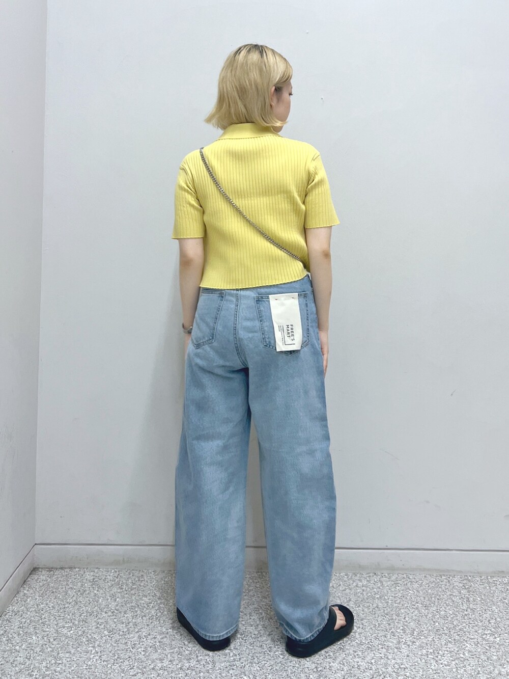 ブルー系のデニムパンツ、ブラック系のショルダーバッグ、イエロー系のニット/セーターを着用したレディースの夏コーディネートの2枚目の写真