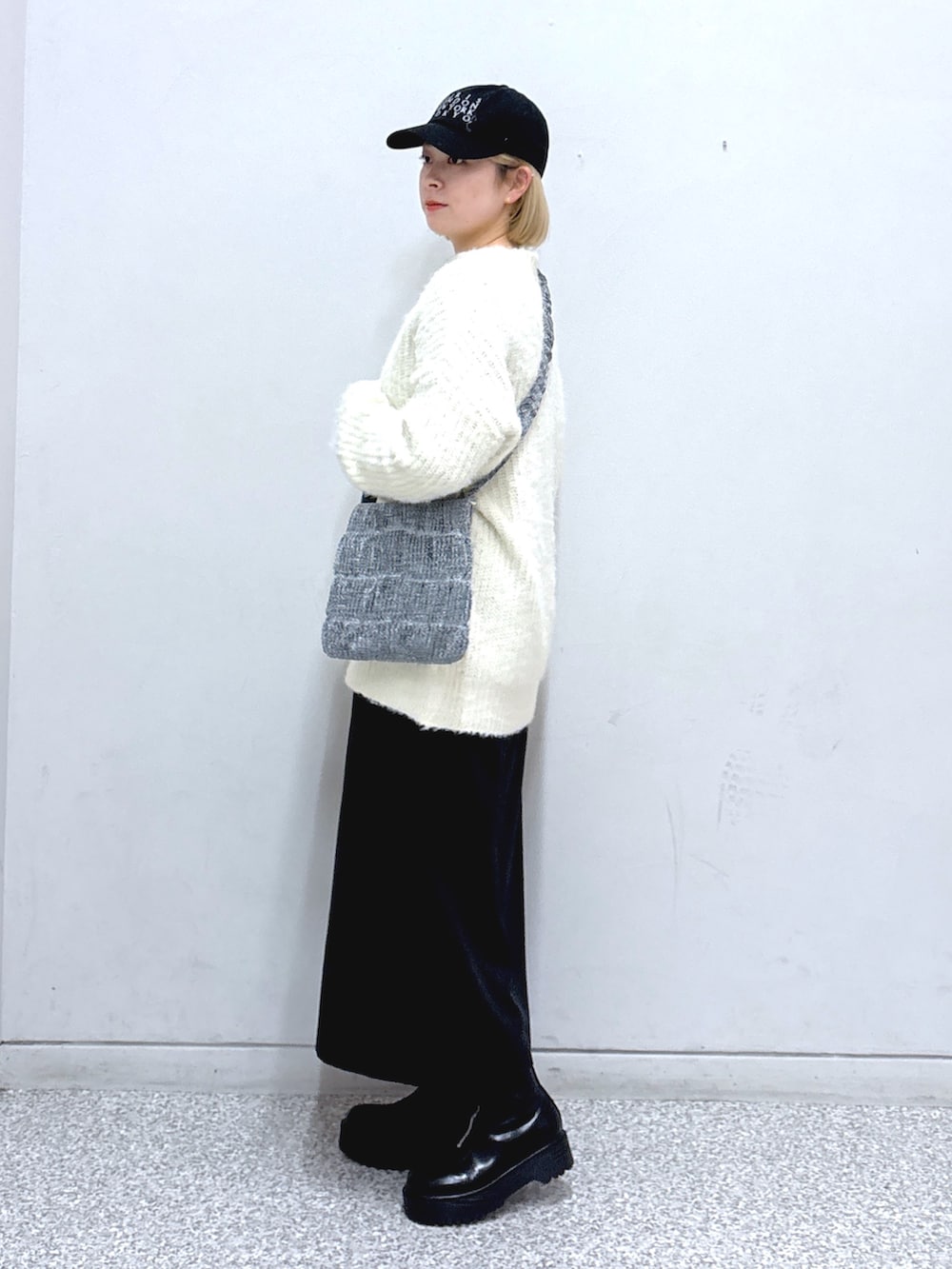 ブラック系のスカート、ホワイト系のニット/セーター、シルバー系のショルダーバッグを着用したレディースの冬コーディネートの2枚目の写真