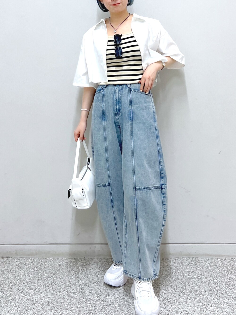 ホワイト系のハンドバッグ、ブルー系のデニムパンツ、ホワイト系のシャツ/ブラウスを着用したレディースの夏コーディネートの4枚目の写真