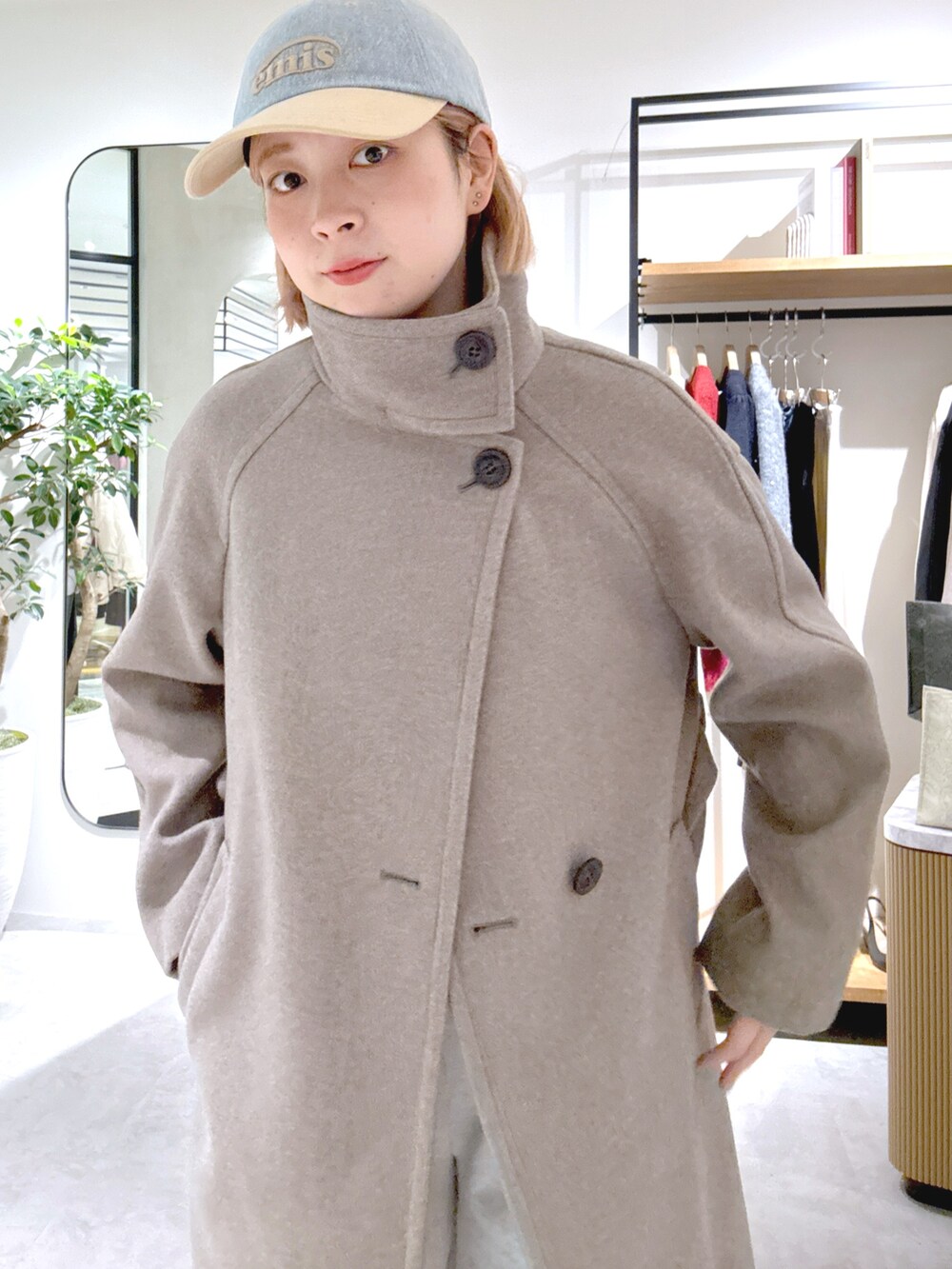 ブラウン系のステンカラーコート、ホワイト系のスウェットパンツ、ブルー系のトートバッグを着用したレディースの秋コーディネートの4枚目の写真