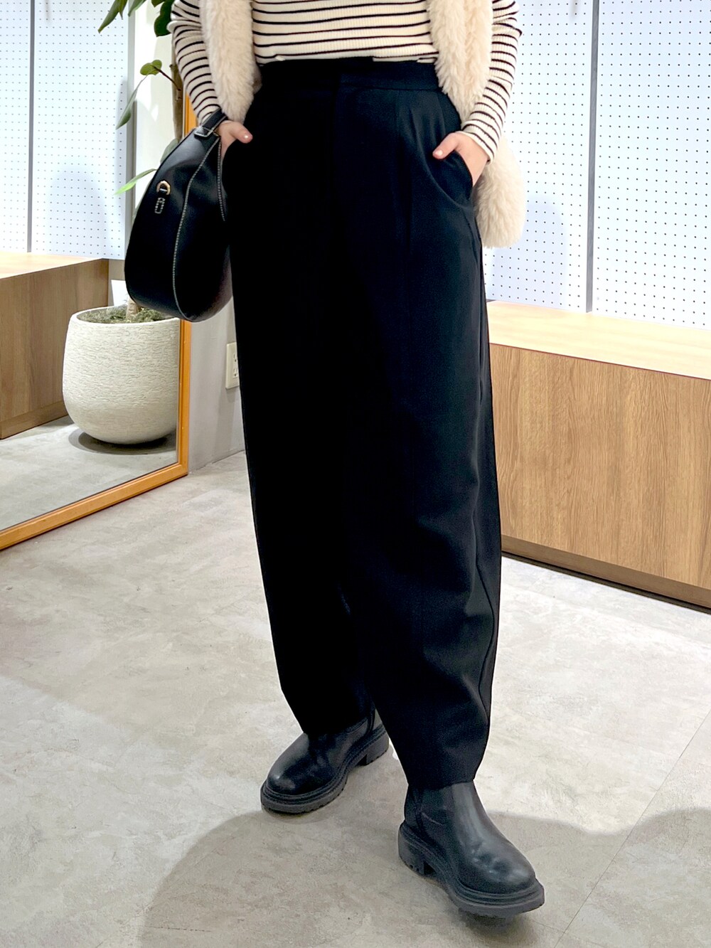 ブラック系のショルダーバッグ、ホワイト系のベスト、ホワイト系のニット/セーターを着用したレディースの秋コーディネートの5枚目の写真