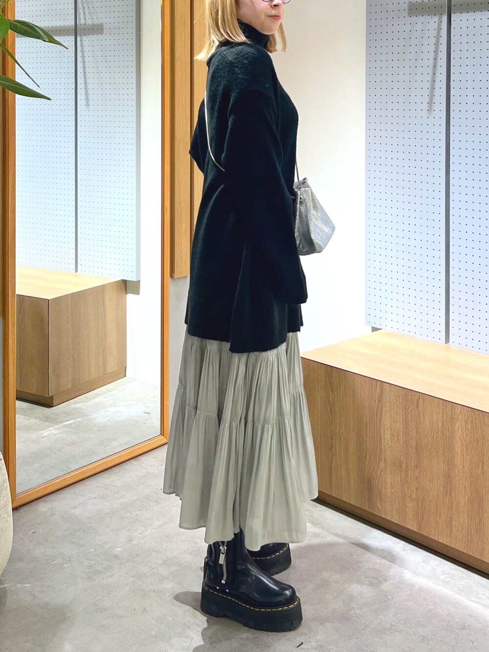 ブラック系のニット/セーター、シルバー系のショルダーバッグ、ホワイト系のスカートを着用したレディースの冬コーディネートの3枚目の写真