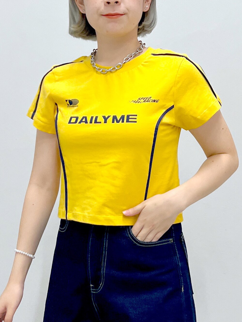 ブルー系のデニムパンツ、シルバー系のハンドバッグ、オレンジ系のTシャツ/カットソーを着用したレディースの秋コーディネートの4枚目の写真