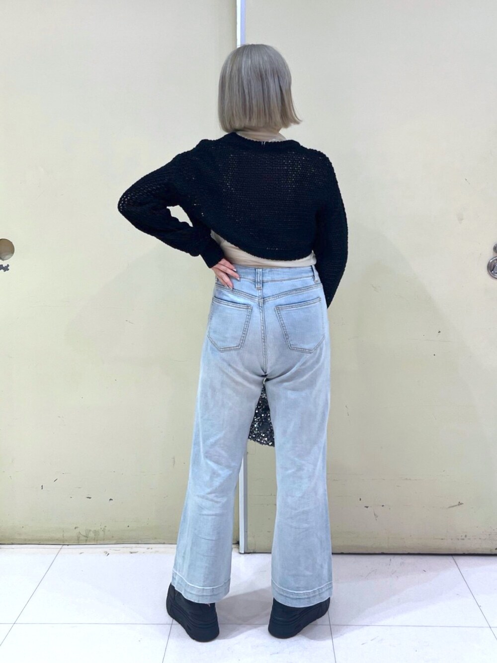 ブラック系のニット/セーター、ブルー系のデニムパンツ、シルバー系のハンドバッグを着用したレディースの春コーディネートの3枚目の写真