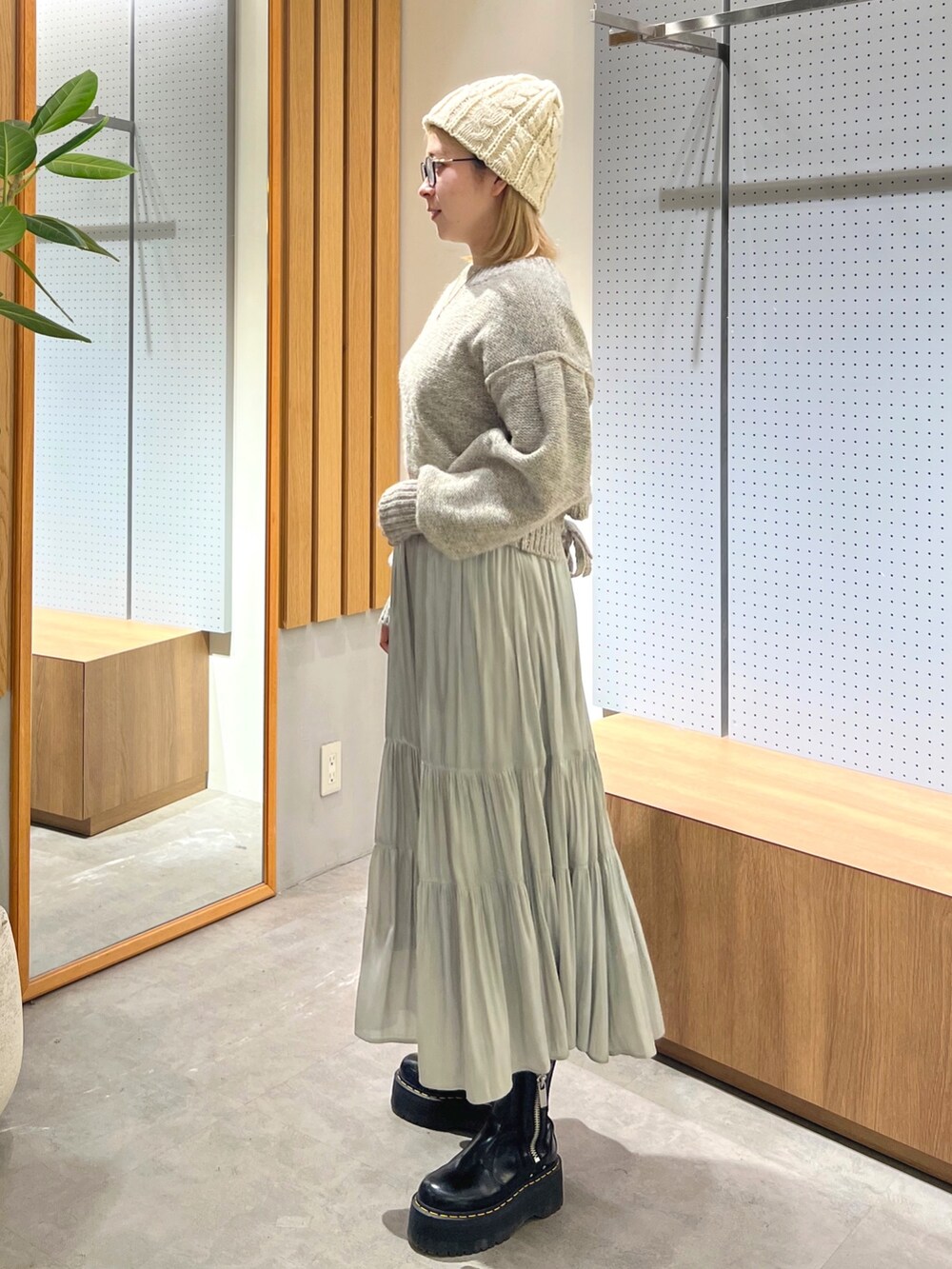 グレー系のニット/セーター、グリーン系のスカート、ホワイト系のニットキャップ/ビーニーを着用したレディースの冬コーディネートの3枚目の写真