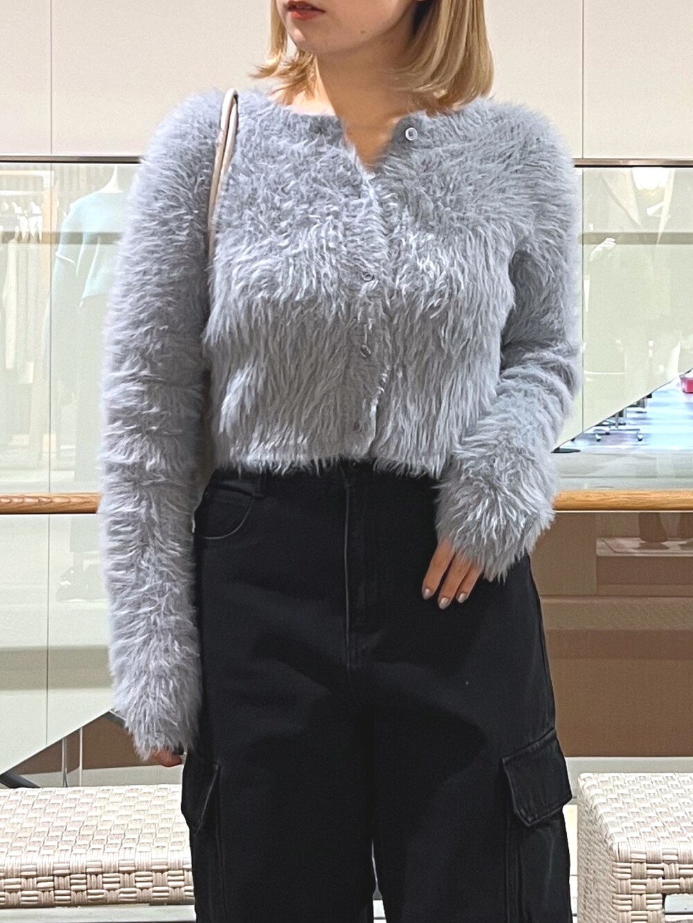 ブラック系のデニムパンツ、ブラック系のローファー、パープル系のショルダーバッグを着用したレディースの冬コーディネートの2枚目の写真