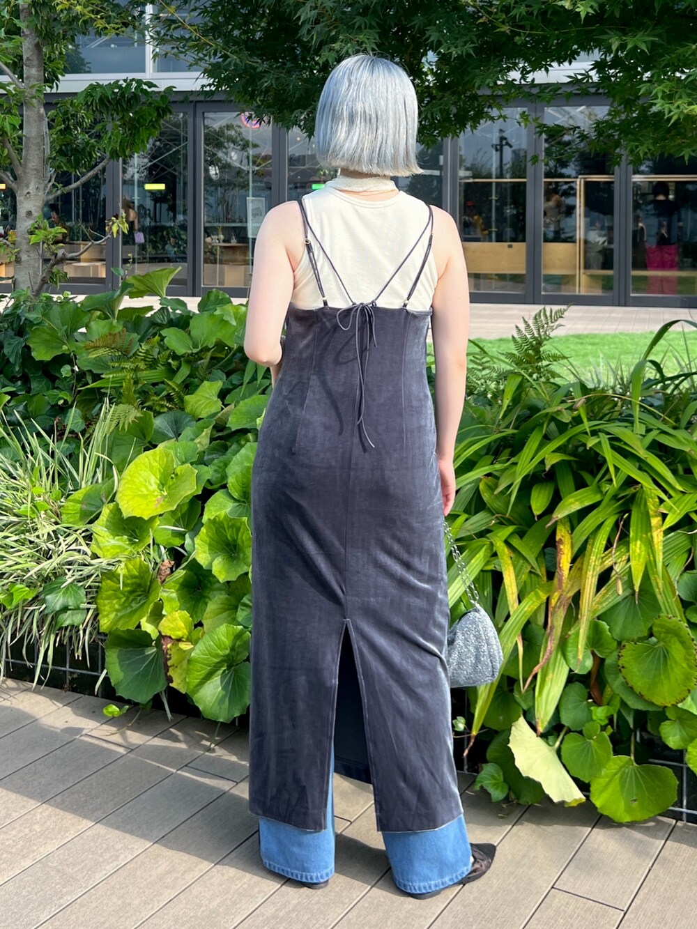 シルバー系のハンドバッグ、ブルー系のデニムパンツ、ホワイト系のタンクトップを着用したレディースの秋コーディネートの3枚目の写真