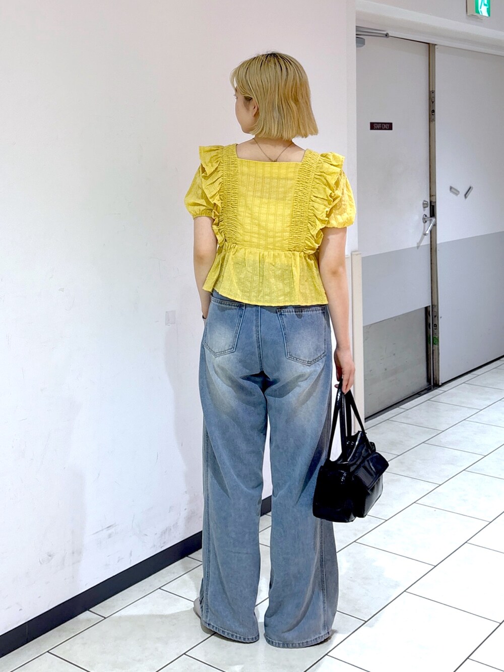 シルバー系のスニーカー、ブルー系のデニムパンツ、イエロー系のシャツ/ブラウスを着用したレディースの夏コーディネートの3枚目の写真