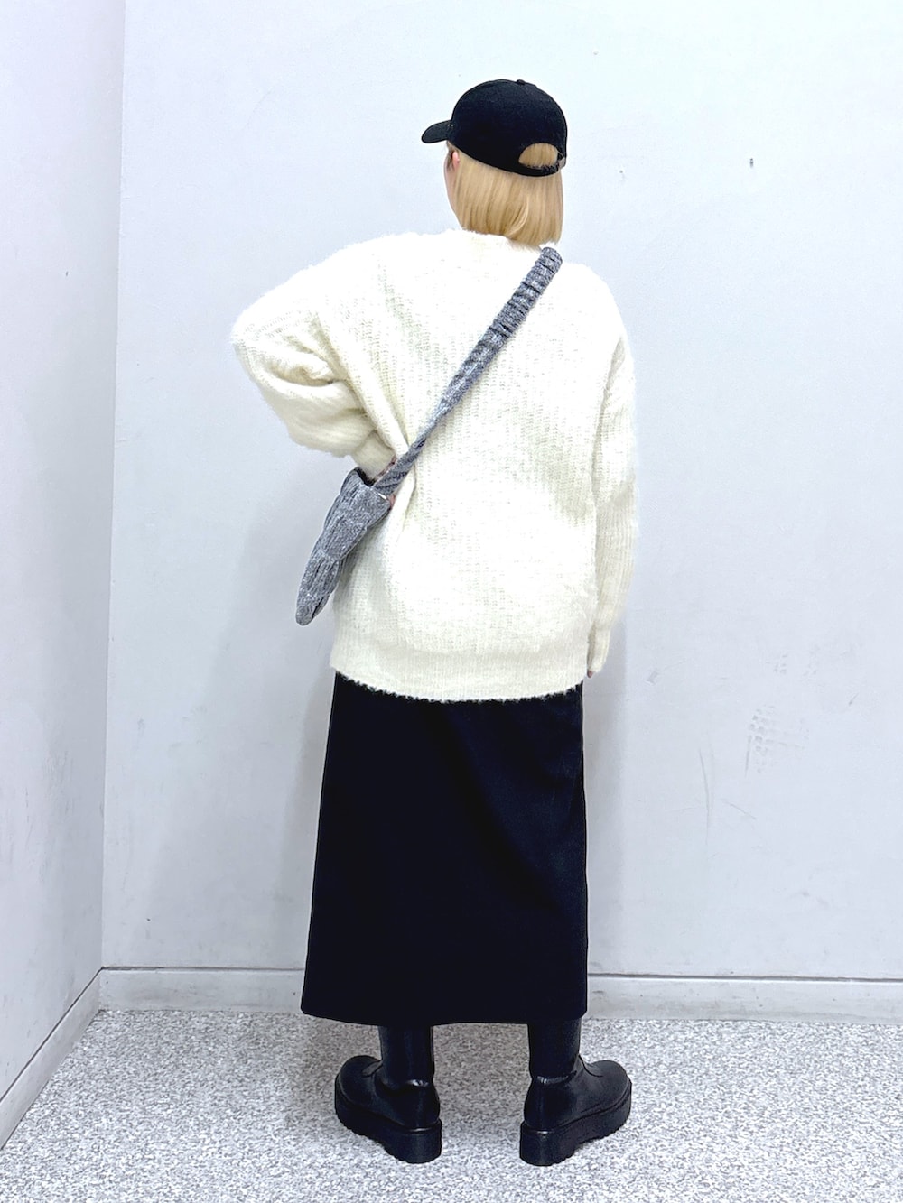 ブラック系のスカート、ホワイト系のニット/セーター、シルバー系のショルダーバッグを着用したレディースの冬コーディネートの3枚目の写真