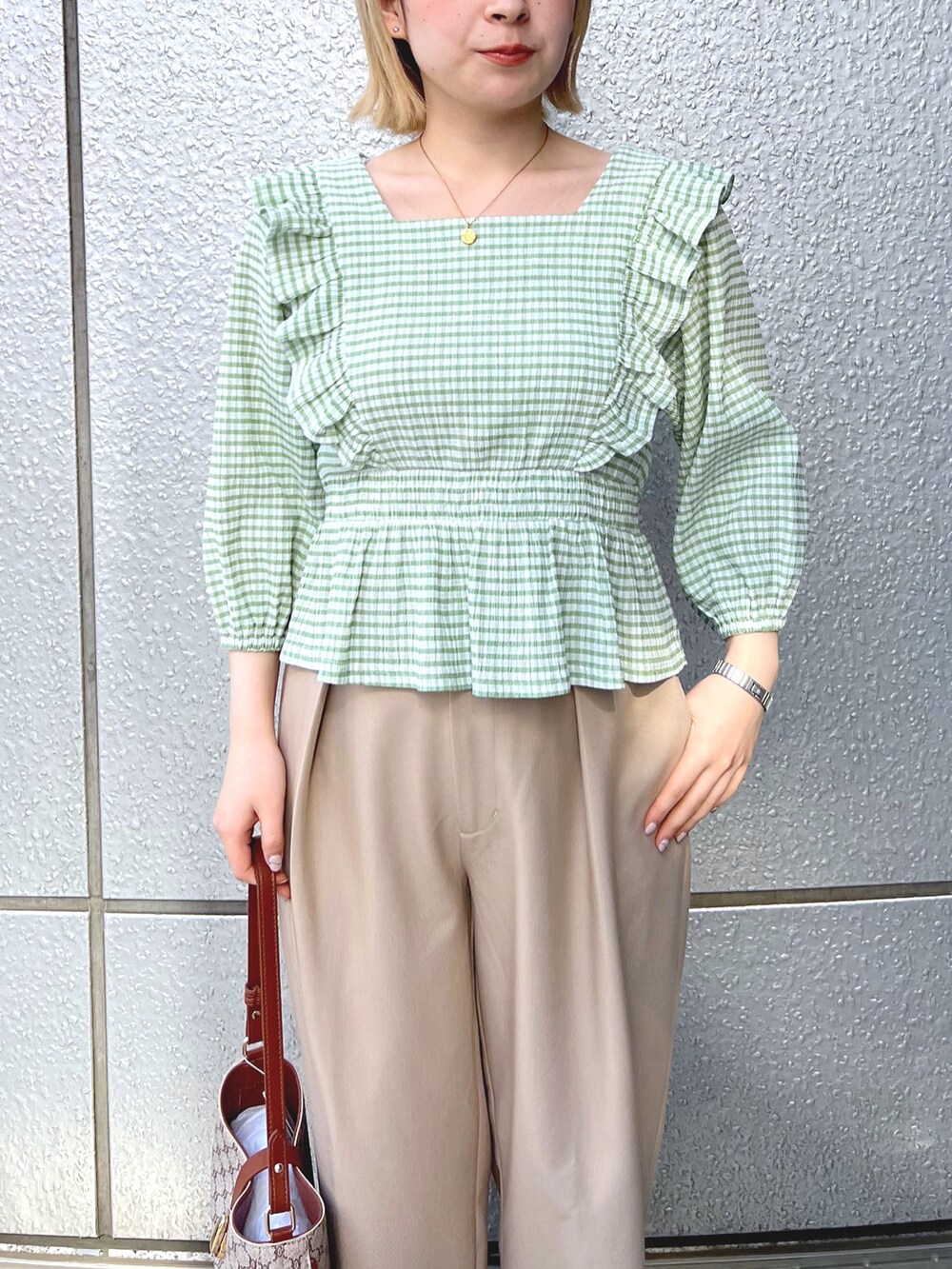 グリーン系のシャツ/ブラウス、ベージュ系のショルダーバッグ、ベージュ系のスラックスを着用したレディースの春コーディネートの4枚目の写真