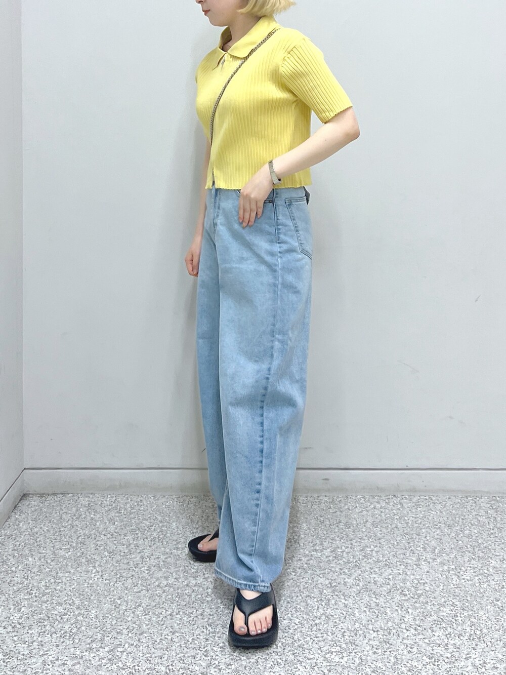 ブルー系のデニムパンツ、ブラック系のショルダーバッグ、イエロー系のニット/セーターを着用したレディースの夏コーディネートの3枚目の写真