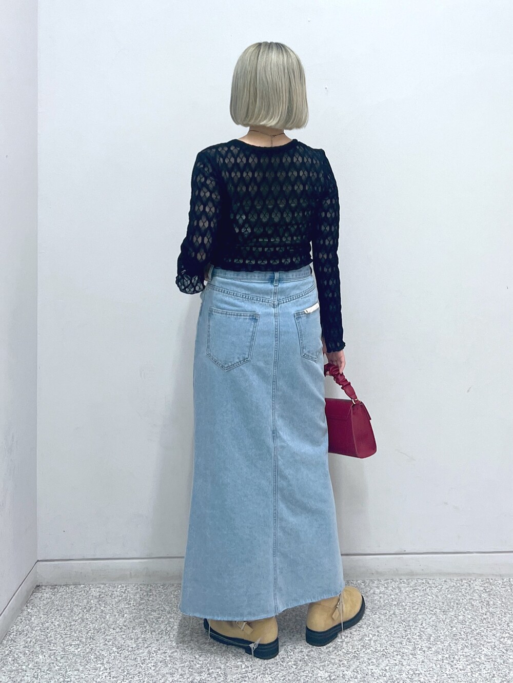 ブルー系のデニムスカート、ベージュ系のブーツ、レッド系のショルダーバッグを着用したレディースの秋コーディネートの3枚目の写真