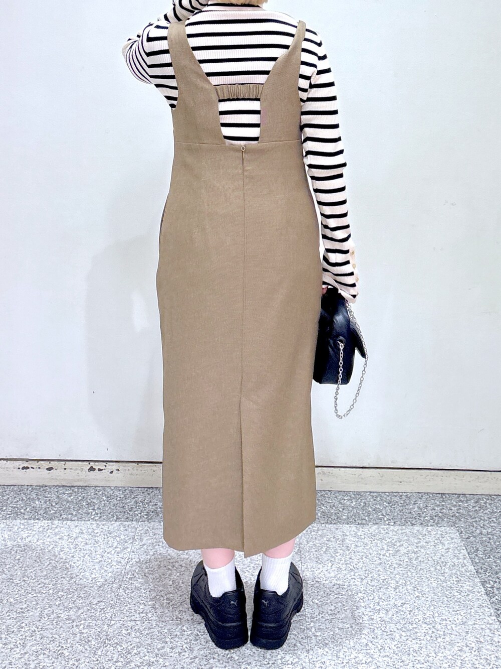 ブラック系のショルダーバッグ、ブラウン系のジャンパースカート、ベージュ系のニット/セーターを着用したレディースの冬コーディネートの6枚目の写真