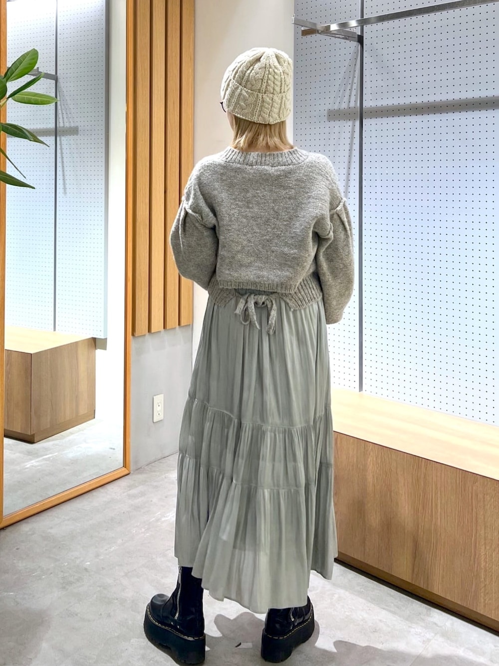 グレー系のニット/セーター、グリーン系のスカート、ベージュ系のショルダーバッグを着用したレディースの冬コーディネートの6枚目の写真