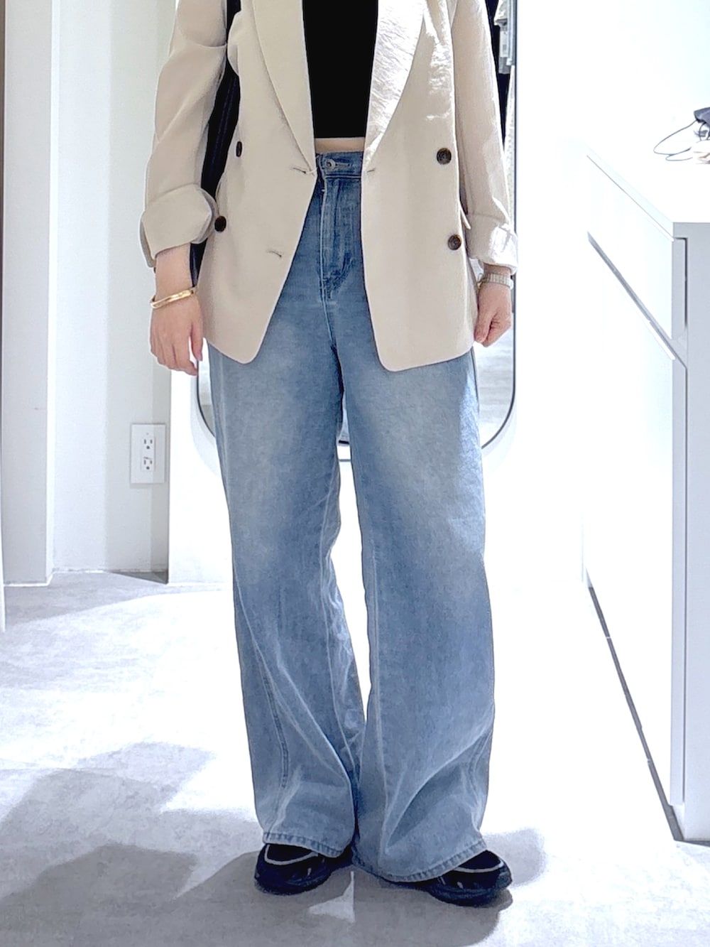 ホワイト系のテーラードジャケット、ブルー系のデニムパンツ、ブラウン系のトートバッグを着用したレディースの春コーディネートの5枚目の写真