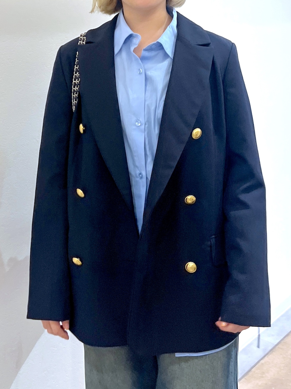 ブラック系のショルダーバッグ、ブルー系のデニムパンツ、ブルー系のテーラードジャケットを着用したレディースの秋コーディネートの5枚目の写真