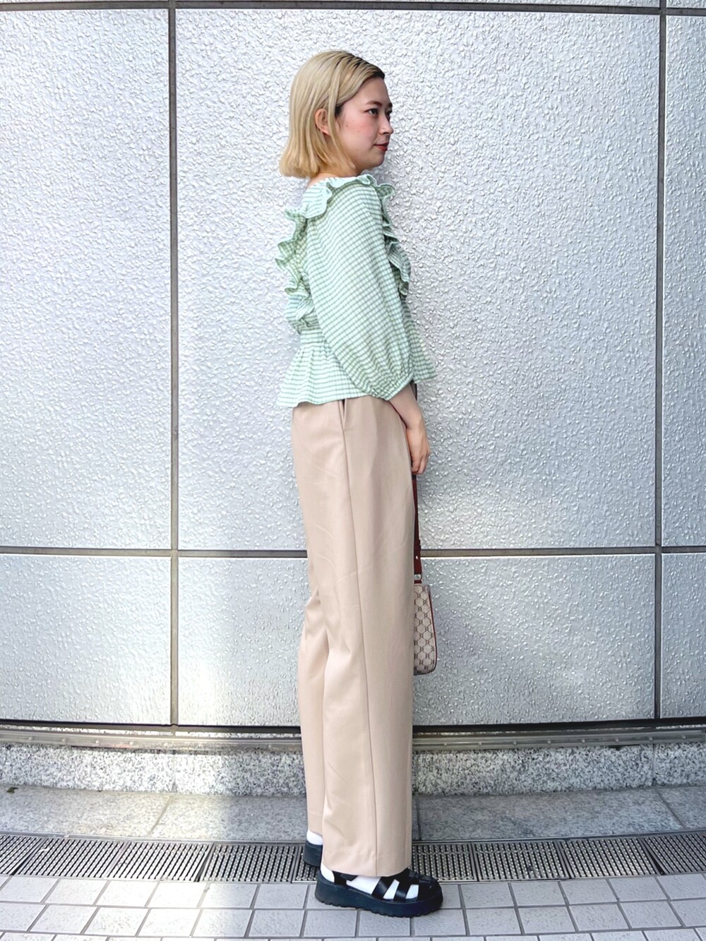 グリーン系のシャツ/ブラウス、ベージュ系のショルダーバッグ、ベージュ系のスラックスを着用したレディースの春コーディネートの2枚目の写真