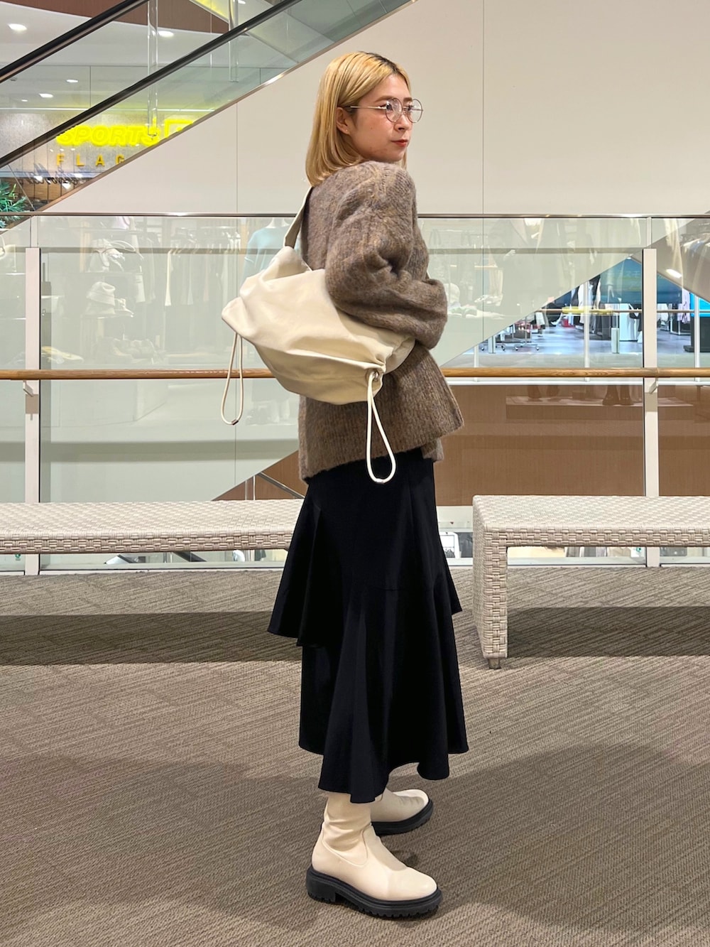 ブラック系のスカート、ベージュ系のニット/セーター、ホワイト系のショルダーバッグを着用したレディースの冬コーディネートの2枚目の写真