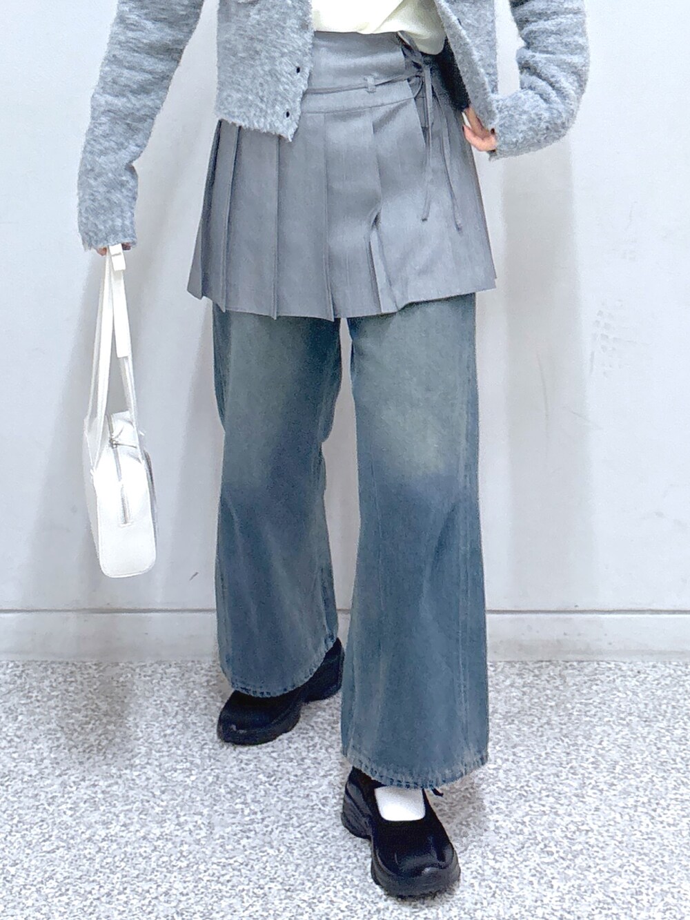 ブルー系のデニムパンツ、グレー系のスカート、グレー系のカーディガン/ボレロを着用したレディースの春コーディネートの6枚目の写真