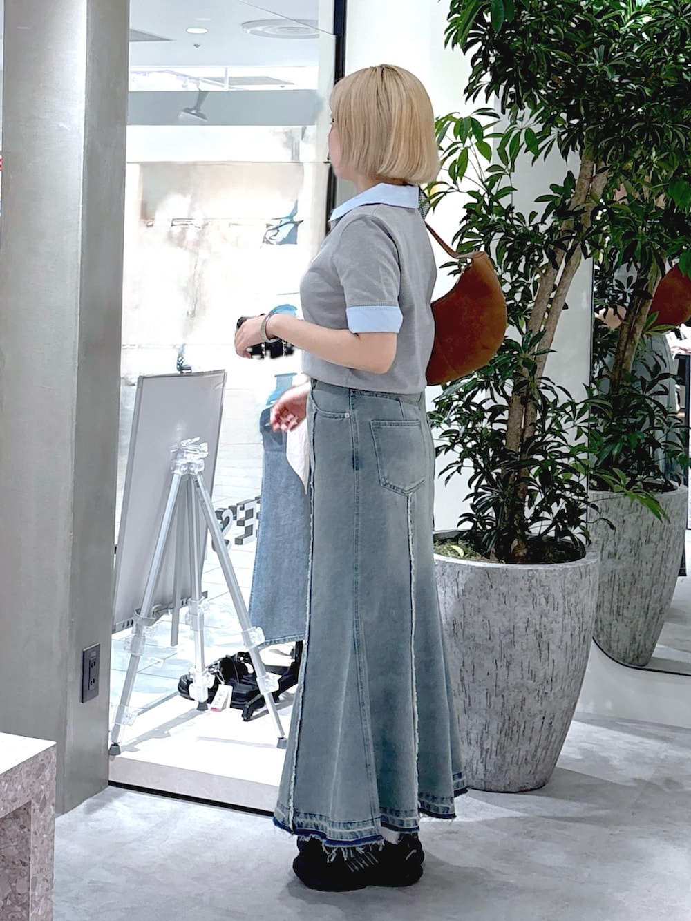 グレー系のニット/セーター、ブルー系のスカート、ブラウン系のハンドバッグを着用したレディースの夏コーディネートの2枚目の写真