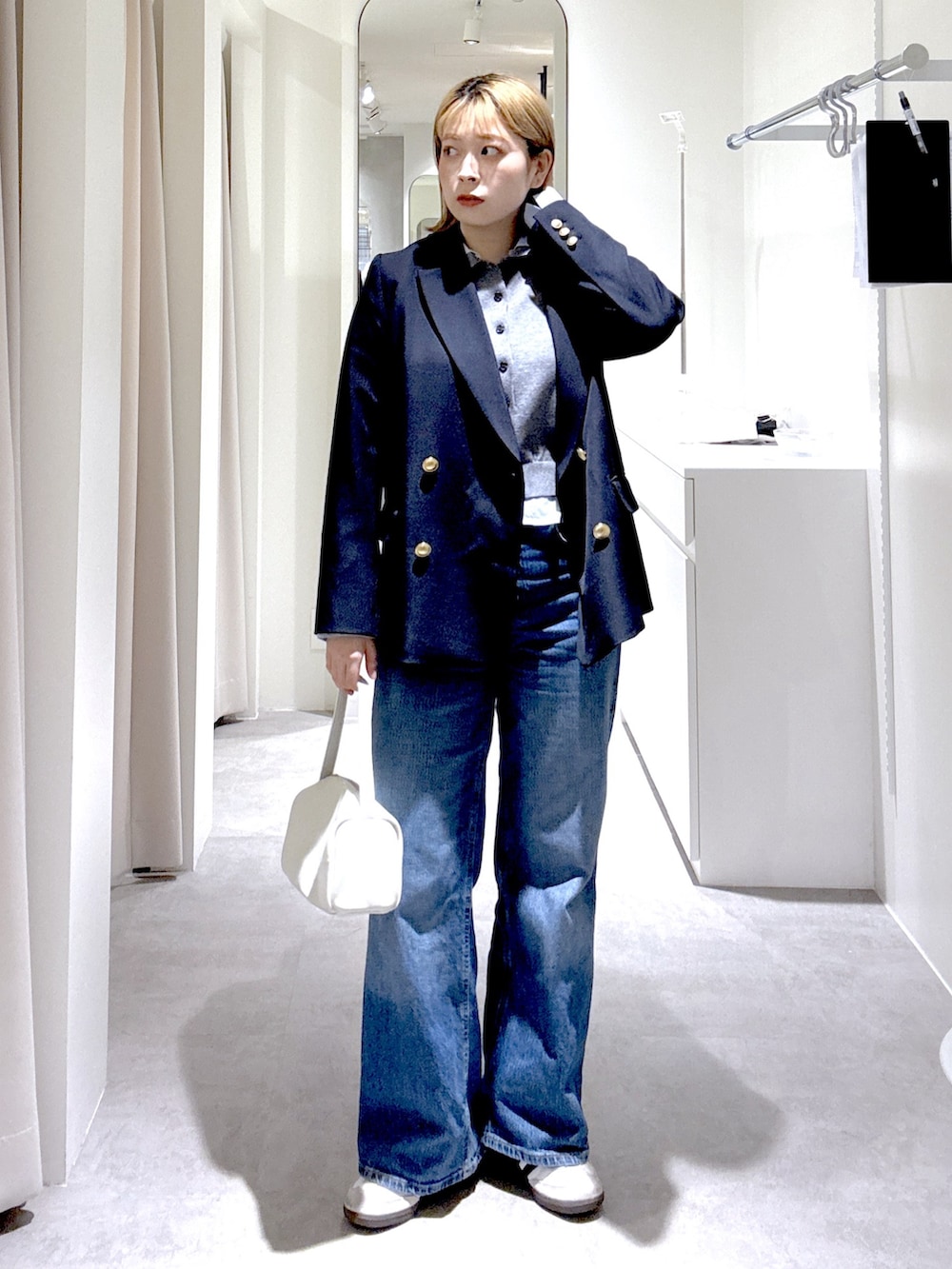 ホワイト系のハンドバッグ、ブルー系のテーラードジャケット、グレー系のニット/セーターを着用したレディースの春コーディネートの4枚目の写真