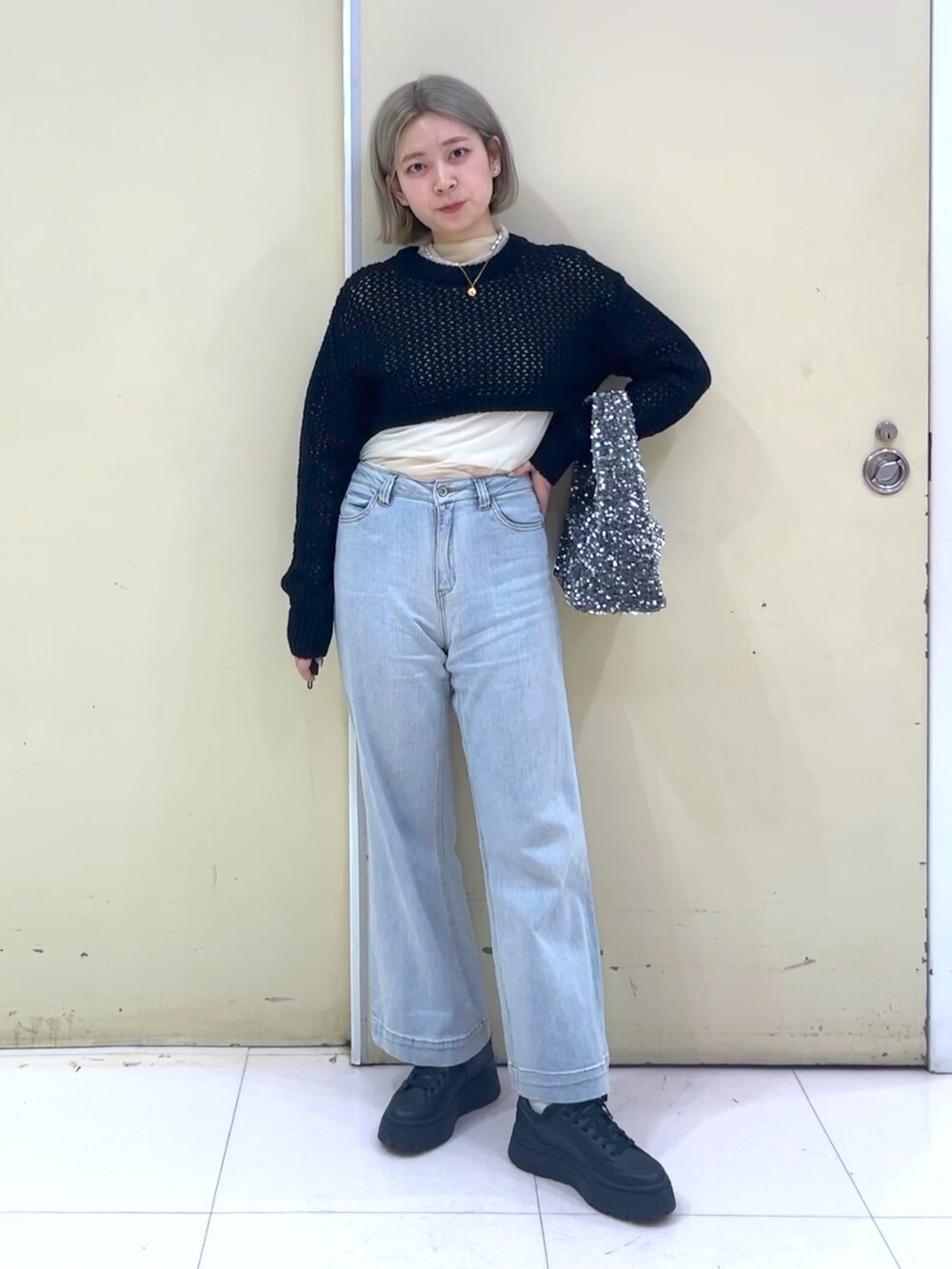 ブラック系のニット/セーター、ブルー系のデニムパンツ、シルバー系のハンドバッグを着用したレディースの春コーディネートの2枚目の写真