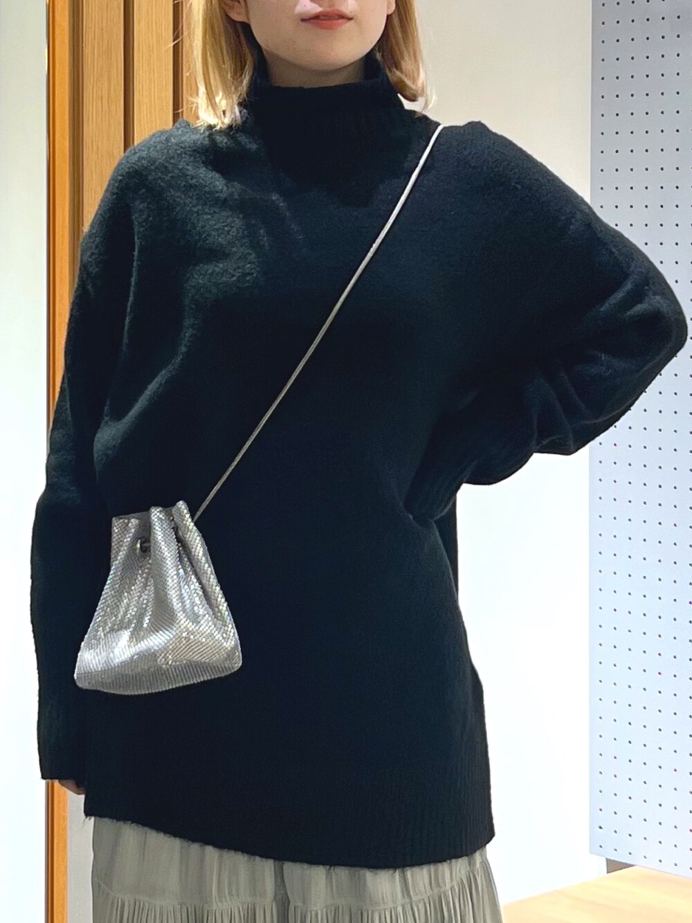 ブラック系のニット/セーター、シルバー系のショルダーバッグ、ホワイト系のスカートを着用したレディースの冬コーディネートの5枚目の写真