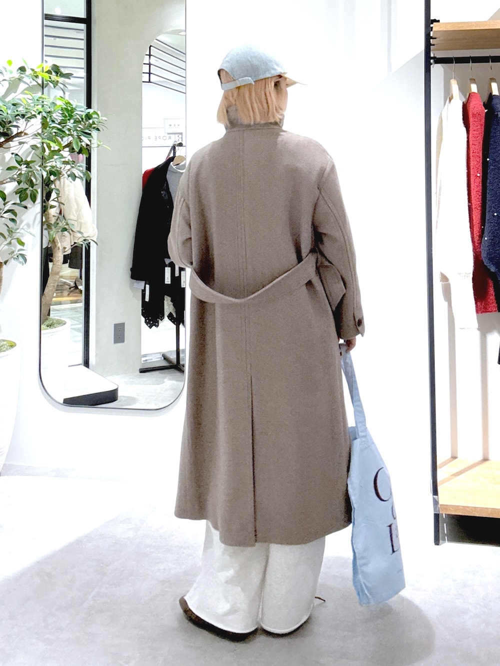 ブラウン系のステンカラーコート、ホワイト系のスウェットパンツ、ブルー系のトートバッグを着用したレディースの秋コーディネートの3枚目の写真