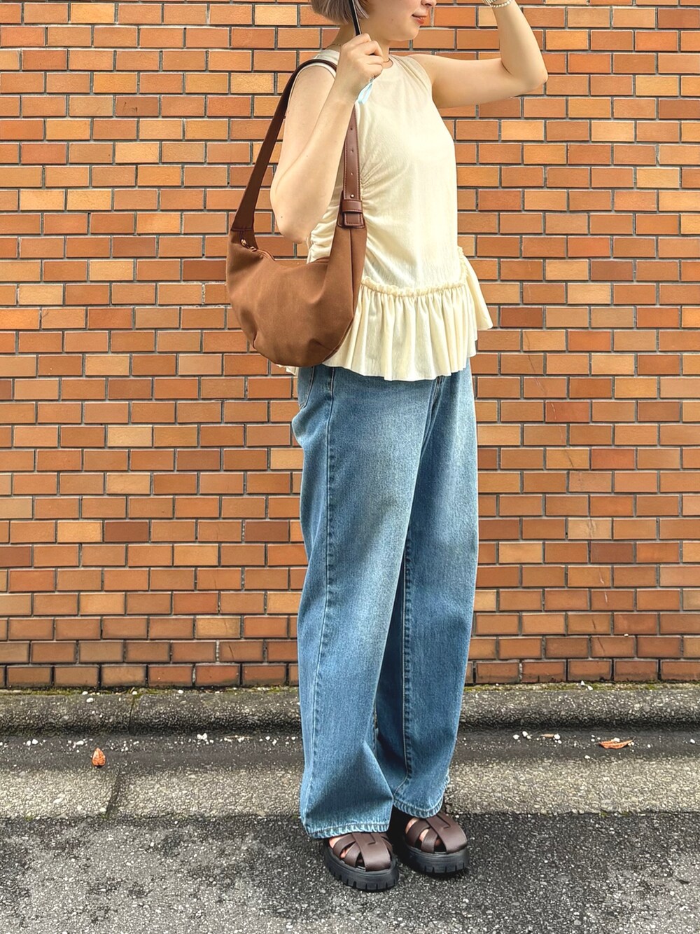 イエロー系のTシャツ/カットソー、ブルー系のデニムパンツ、ブラウン系のサンダルを着用したレディースの夏コーディネートの2枚目の写真